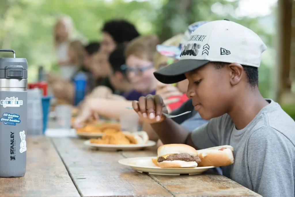 Focus on a young camper at a table eating