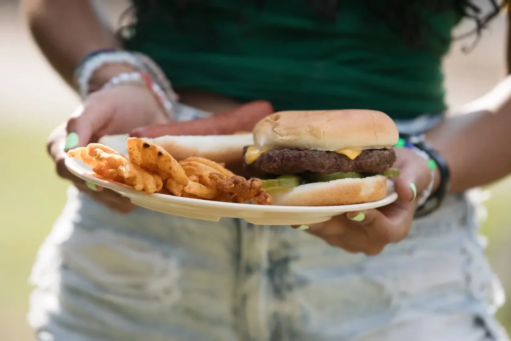 Close up of a plate held by a camper with a burger and waffle fries