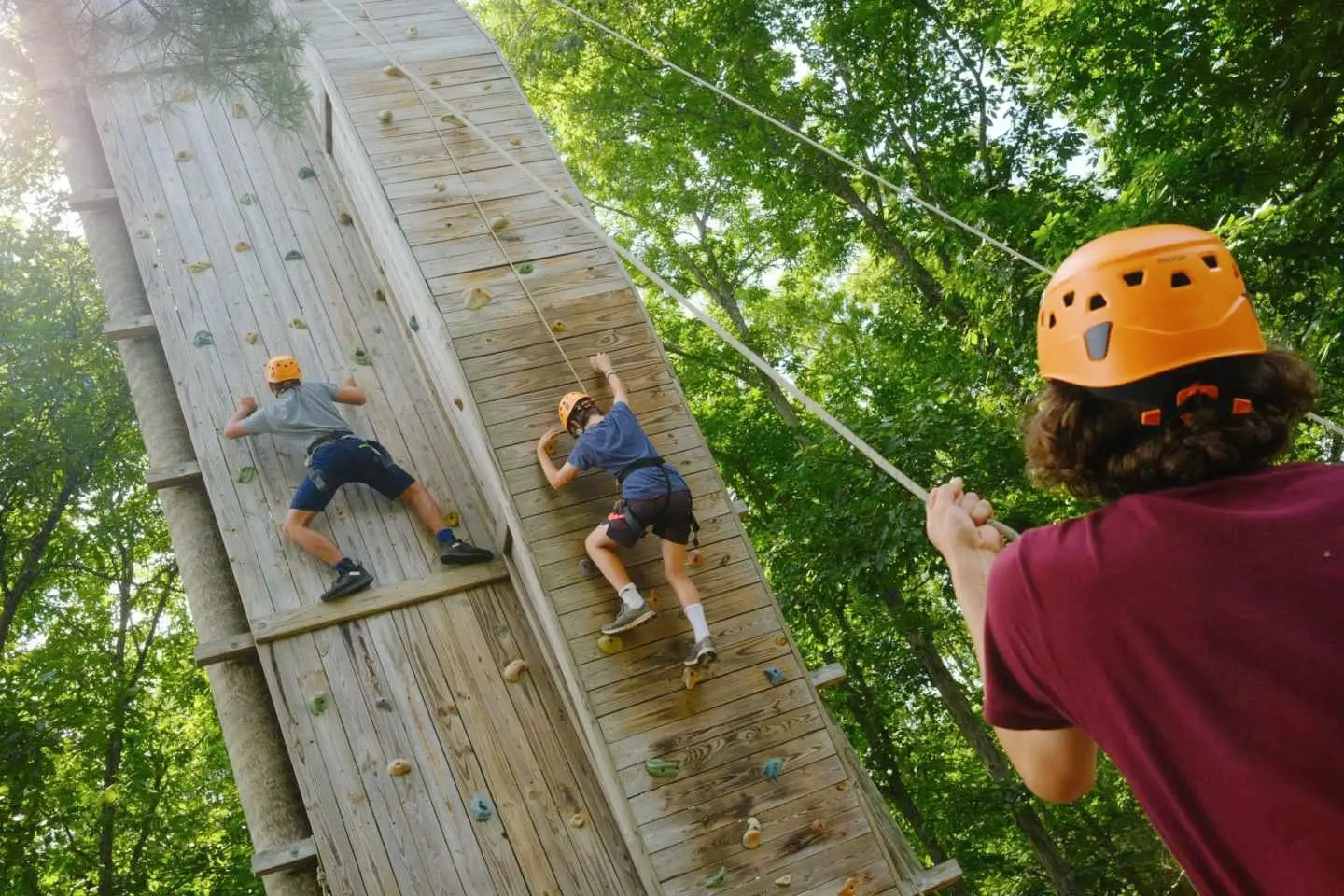 Campers climb on a climbing wall at camp twin creeks